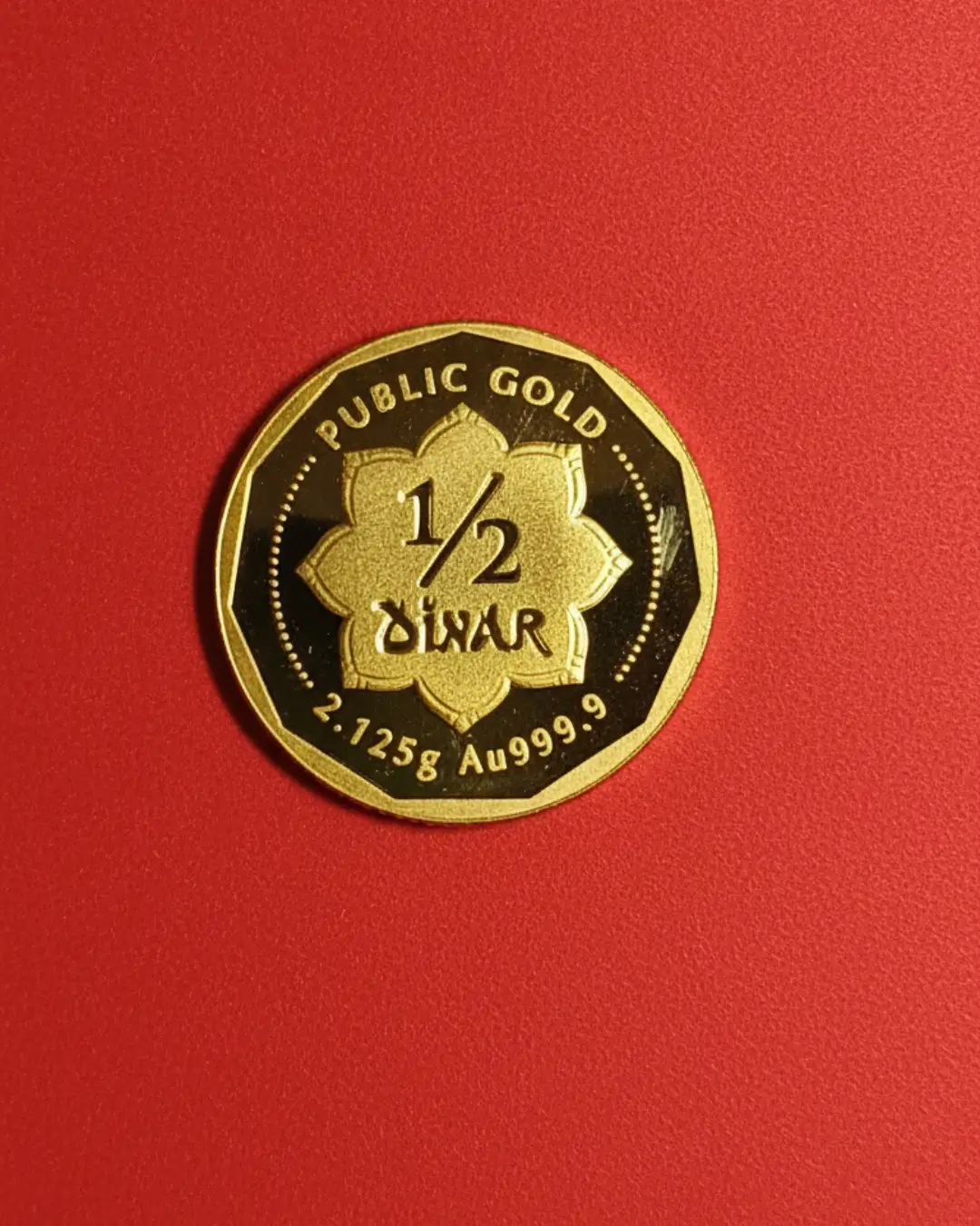Koin emas Public Gold 1/2 Dinar 2,125g Au999.9 pada latar belakang merah